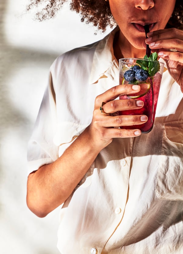 Женщина пьет через соломинку из стакана черничный сироп DRYCK BLÅBÄR