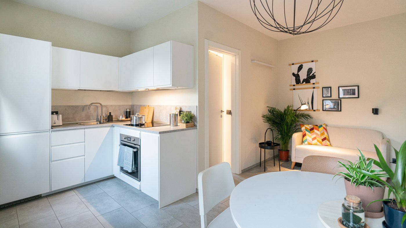 Una panoramica dell'appatamento che comprende la cucina ad angolo componibile con mobile base con ripiani METOD, un tavolo rotondo DOCKSTA e l'ingresso.