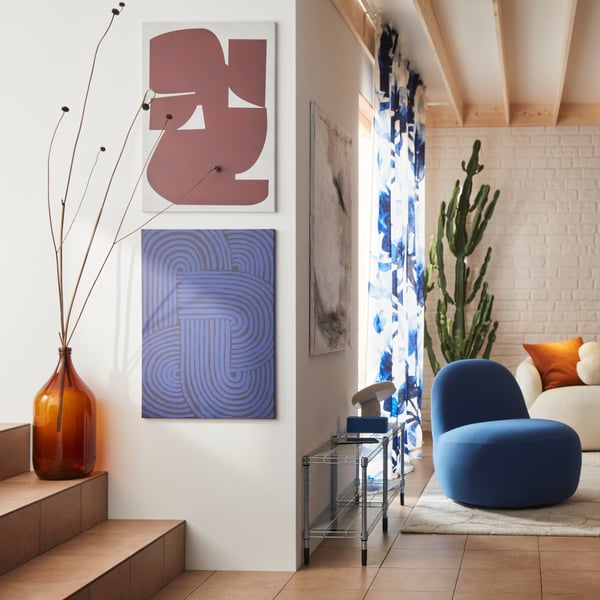 A living room features a Gunnared dark blue LILLESÄTER swivel easy chair made from fabric, beside two PJÄTTERYD pictures.