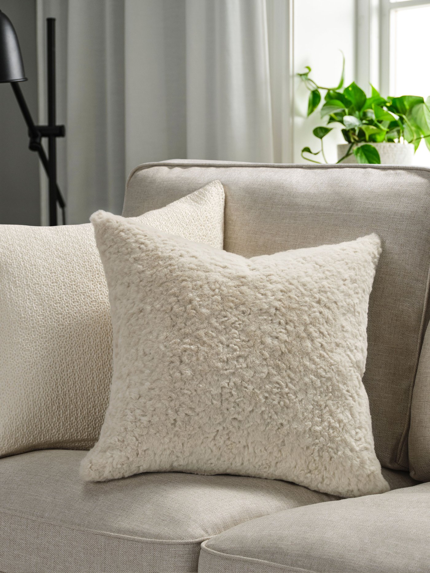 Une housse de coussin beige sur un canapé gris