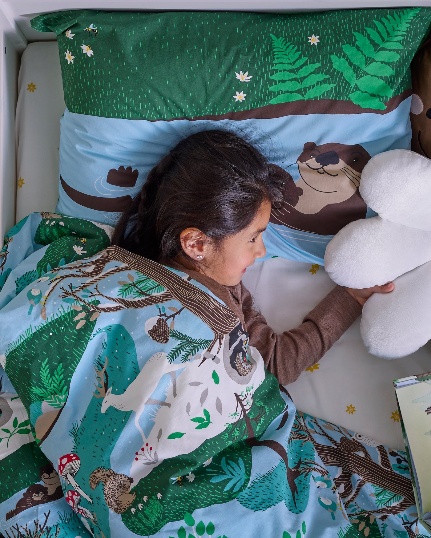 A flower-shaped/white SKOGSDUVA cushion in the childrens room