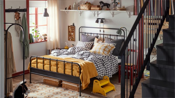 Family bedroom with STJÄRNÖ bed frame in anthracite with checkered sheets. Bedspread and details in bright yellow.