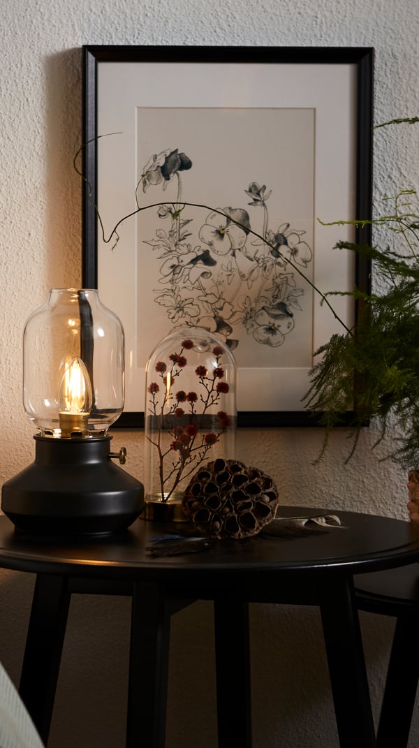 Ett litet sidobord med en bordslampa i gammaldagss stil. 
