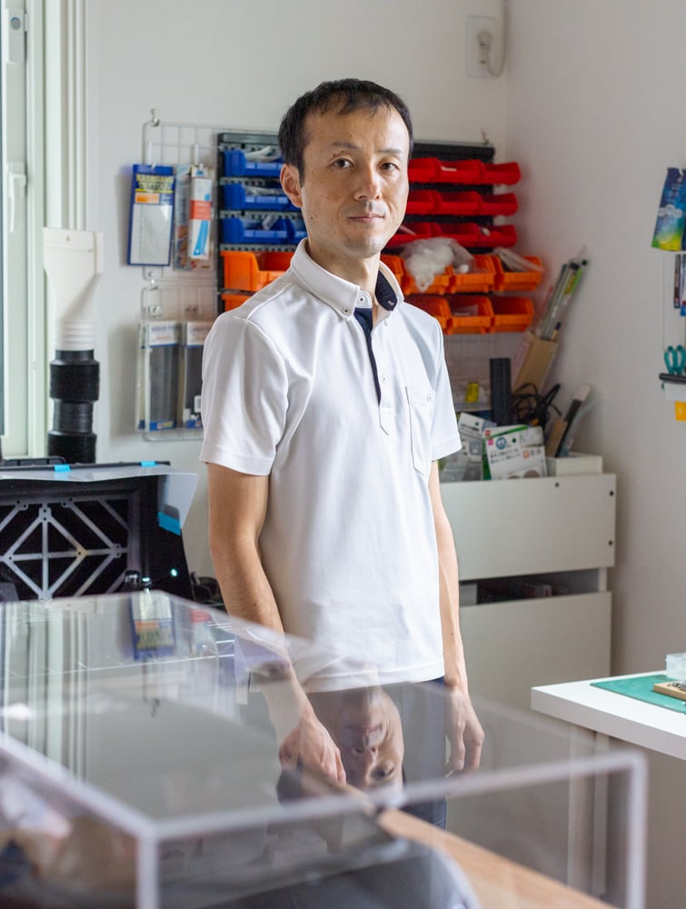 Man standing in his office space, surrounded by well organised tools and items.