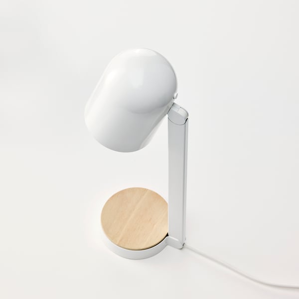 En hvid ENSMÄRKE skrivebordslampe med en rund skærm og en træfod, elegant placeret på en lys baggrund.
