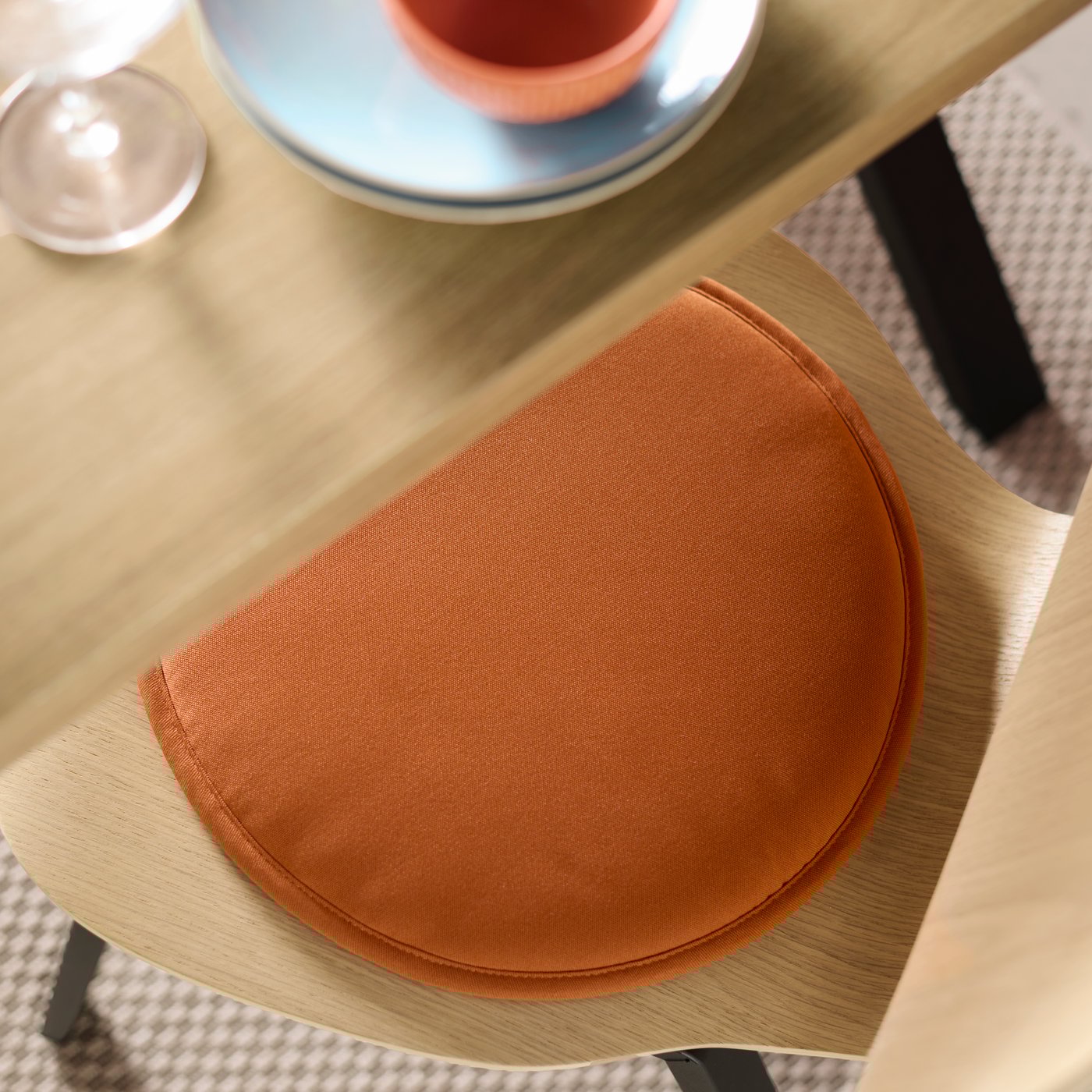 A SKÅLSTA chair has a black-grey underframe with a seat shell in oak veneer and an ÄNGSFRÄKEN chair pad in brown-red.