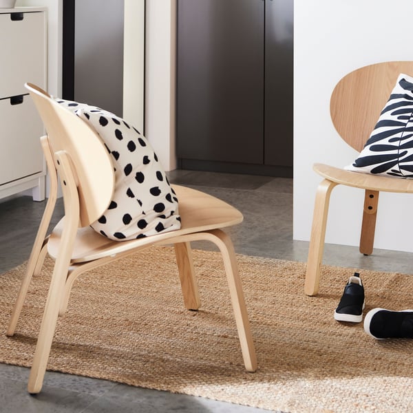 On a LOHALS rug are two FRÖSET chairs with MAJSMOTT cushions. In the background are dark-gray PAX wardrobes.