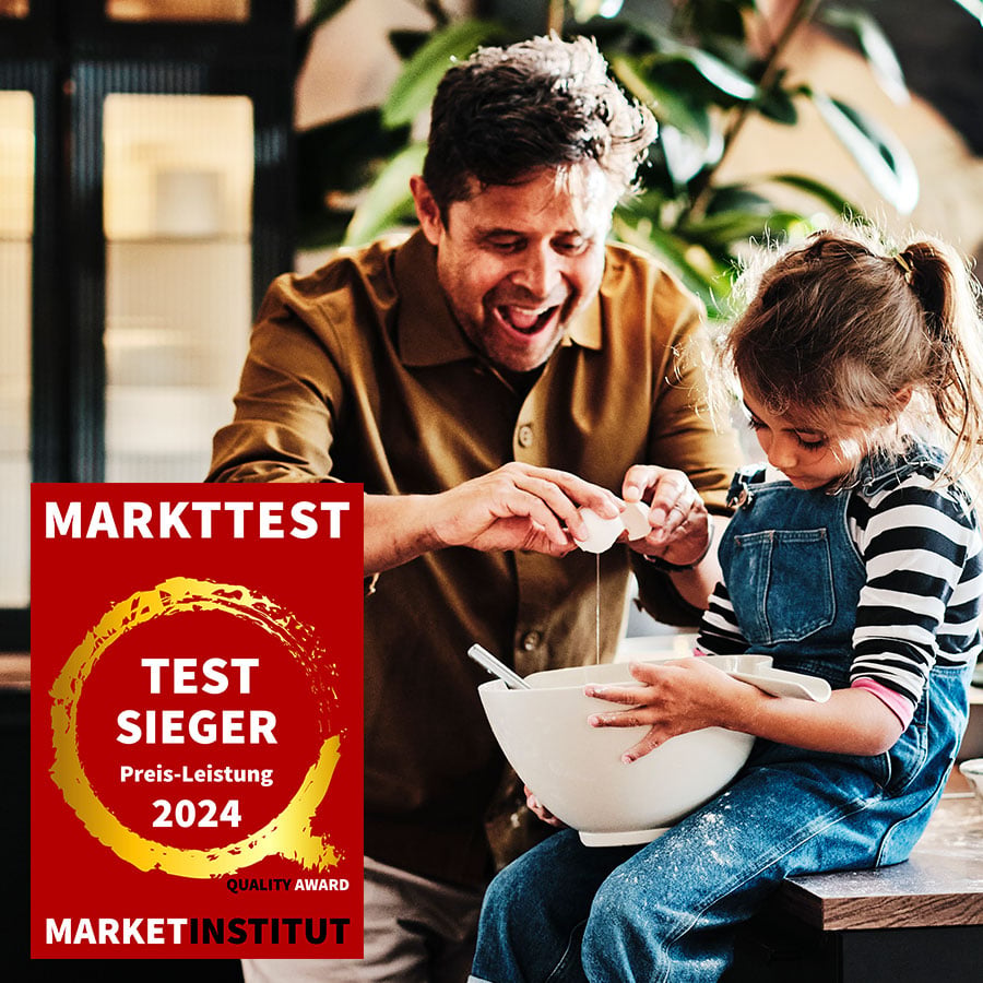 Man sieht einen Mann mit einem Kind beim Backen. Im Vordergrund sieht man das Markttest Logo mit dem Hinweis Testsieger Preis-Leistung 2024