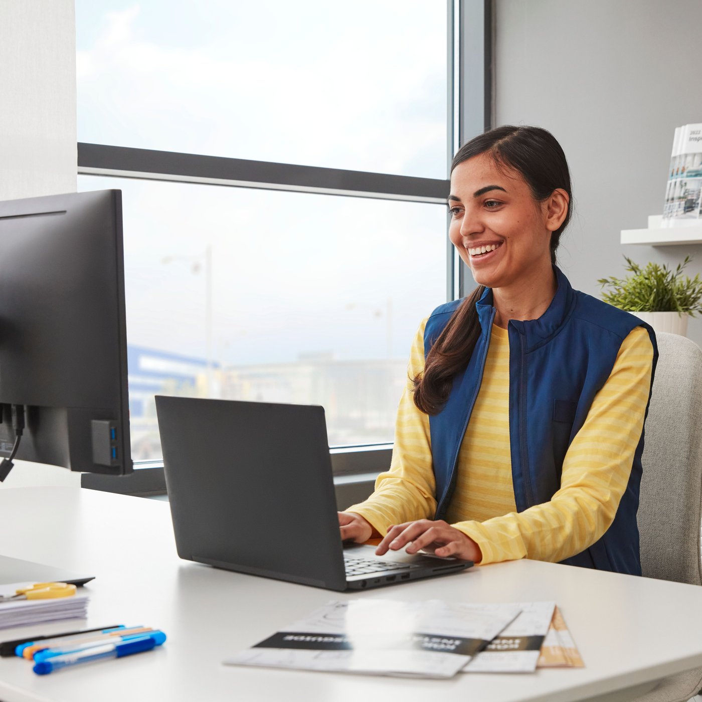 Eine Person sitzt lächelnd an einem Laptop