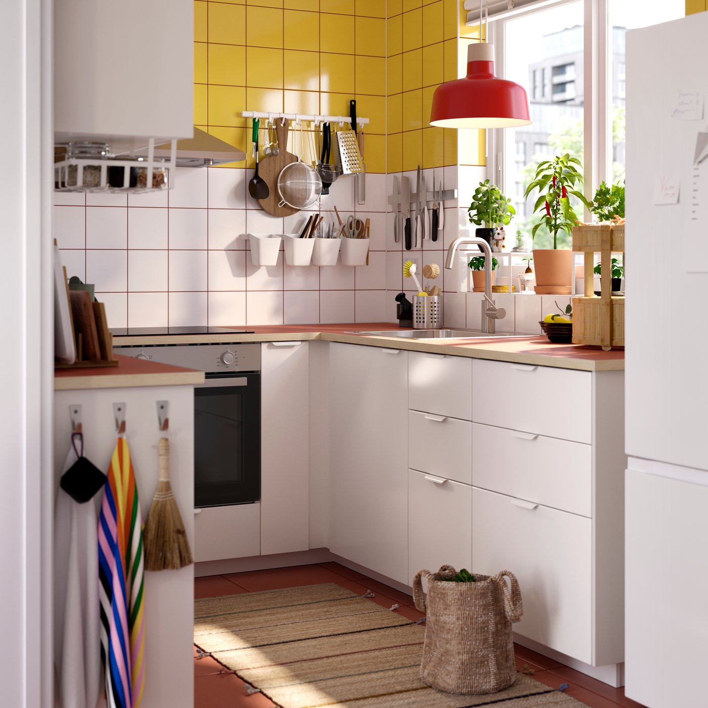 A kitchen with VEDDINGE white drawer fronts and doors, plants in the window, items hanging from the wall and a ceiling lamp.