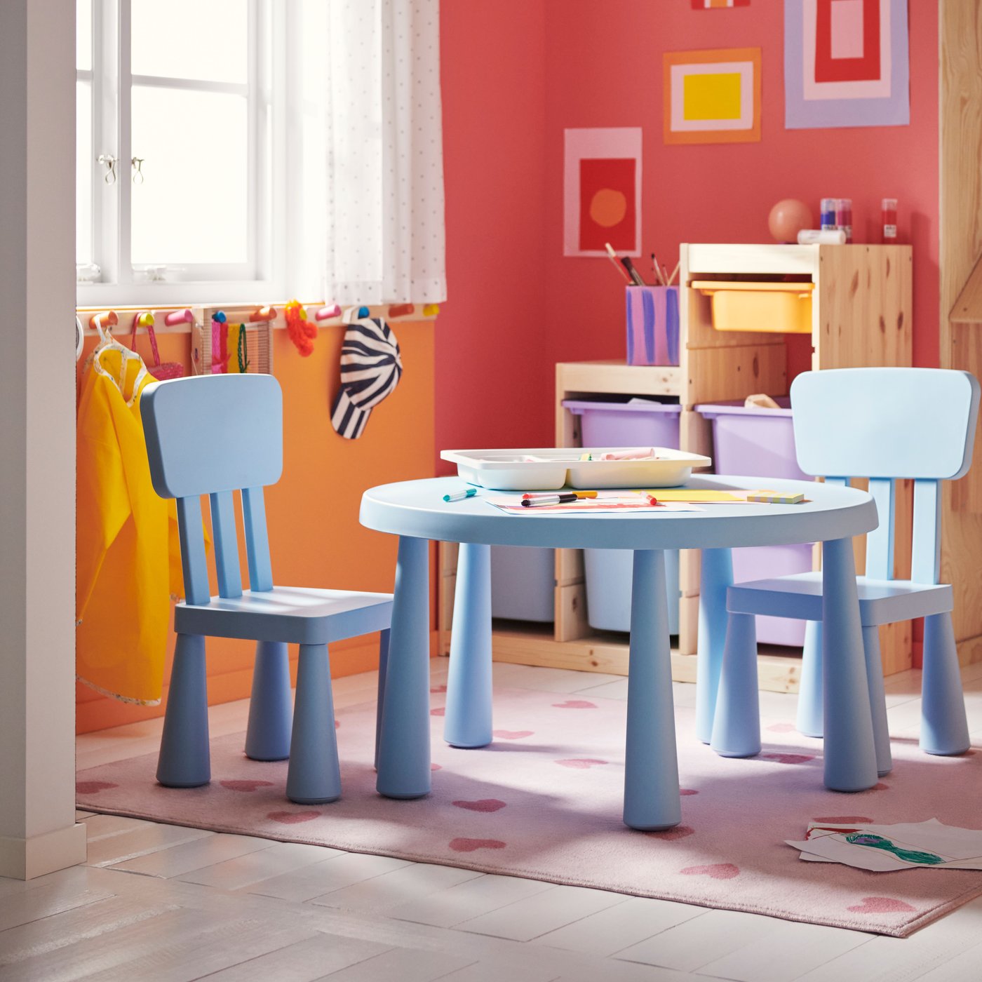 Ein Spielzimmer zeigt einen hellblauen MAMMUT Kindertisch mit zwei passenden Stühlen, umgeben von farbenfroher Wandkunst.