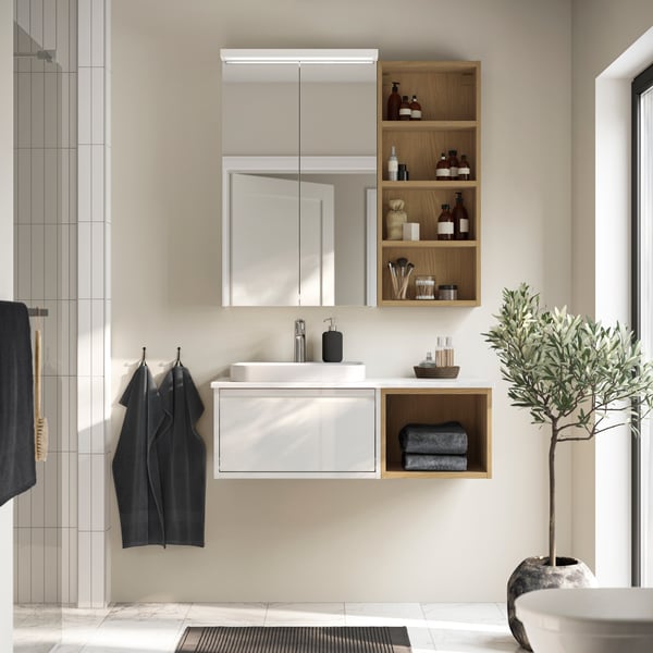 A bathroom with an ÄNGSJÖN wash-stand with drawer in high-gloss white and a HAGAÅN open cabinet under a mirror cabinet.