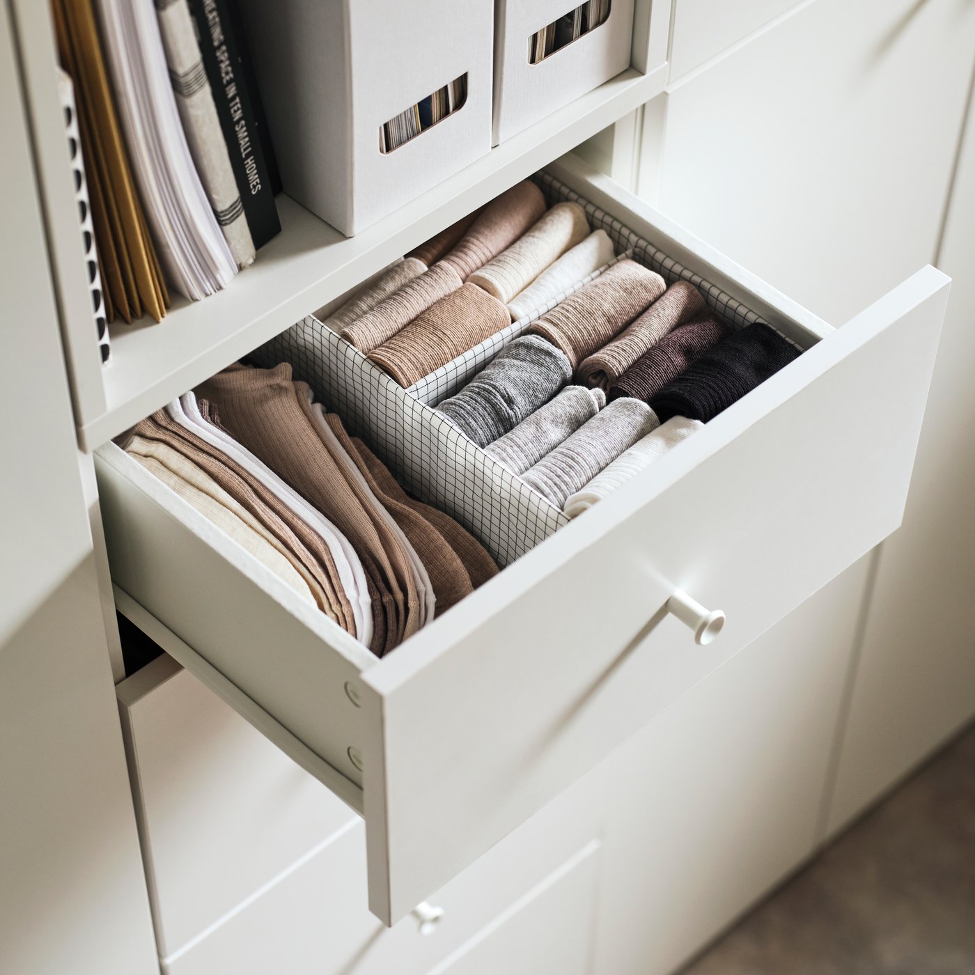 A drawer in a white wardrobe filled with a STUK box with compartments holding neatly folded socks.