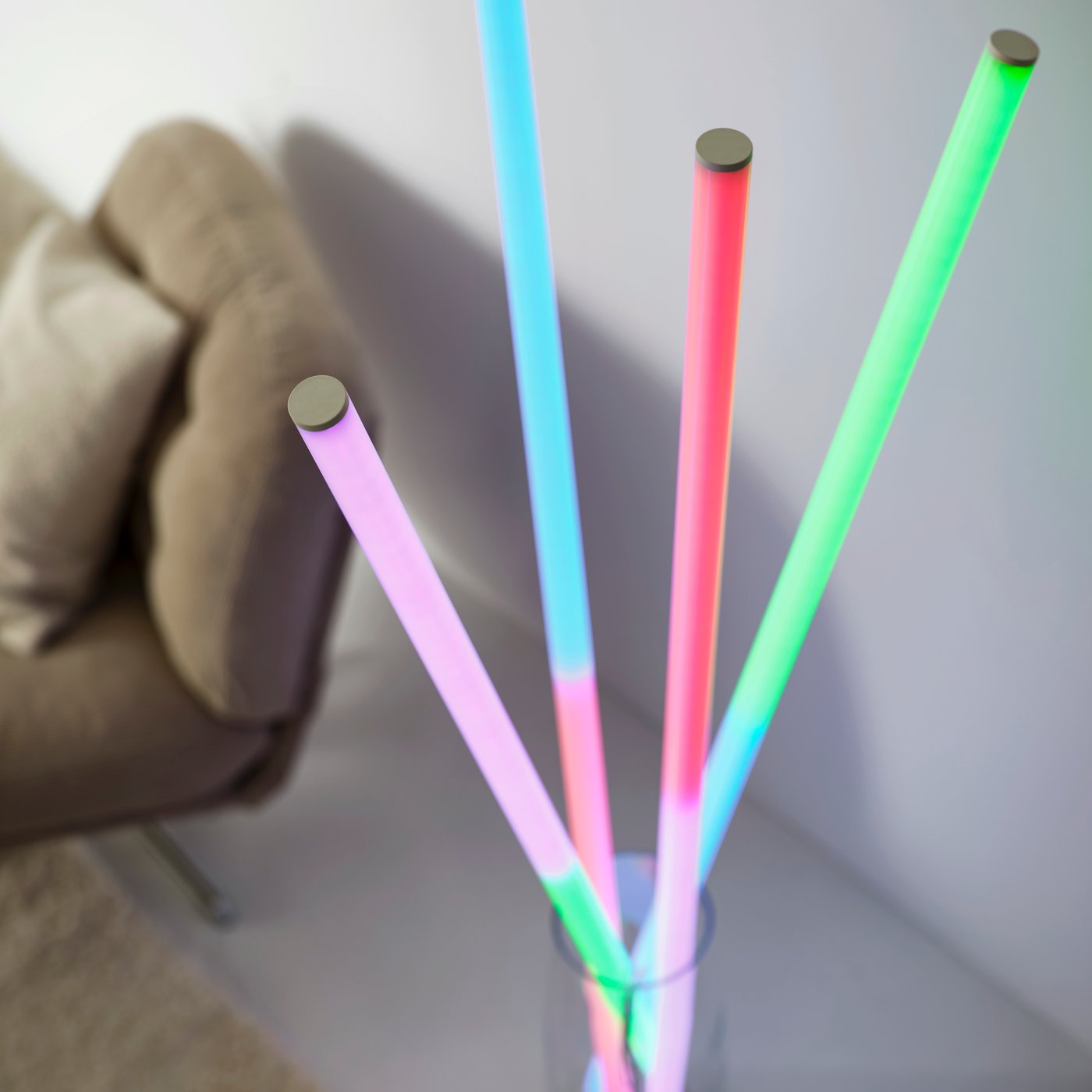 Four FÖRLIG LED floor/wall lamps placed in a large glass vase, each lamp glowing in two different colors.