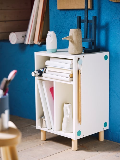 Close-up of multiple books, papers and accessories inside a SMUSSLA bedside table, with a SPIKEN LED night light on top.