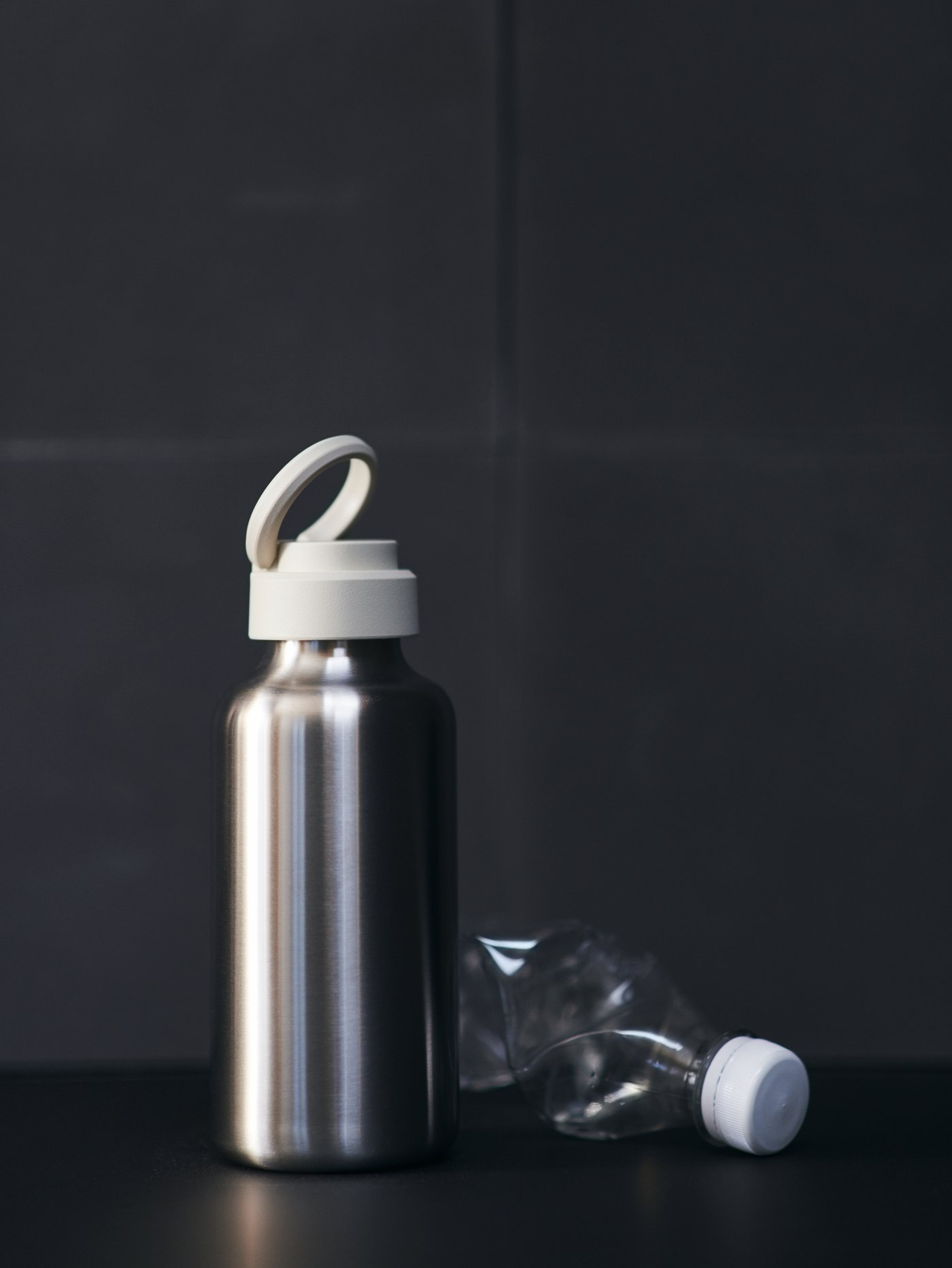 An ENKELSPÅRIG water bottle on a kitchen counter, with a discarded plastic water bottle in the background.