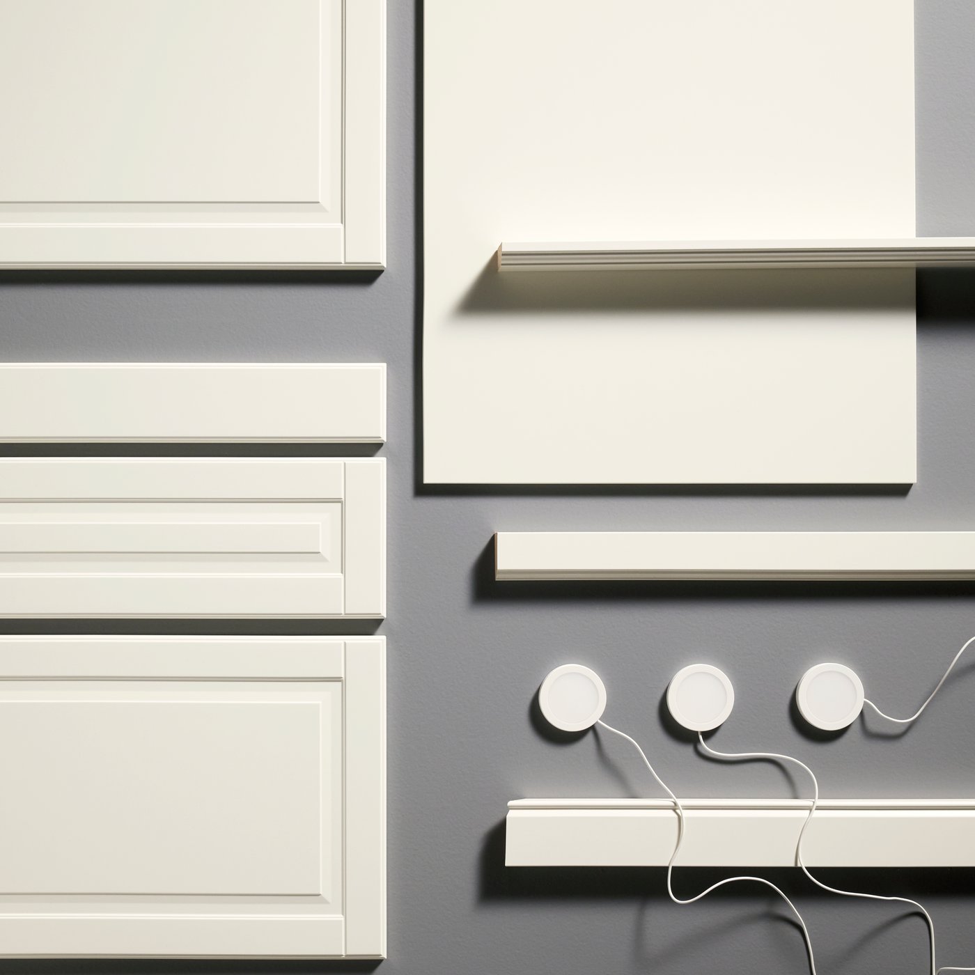 A set of kitchen elements with the FÖRBÄTTRA cover panel in off-white, shown beside strips, lighting, and a plinth.