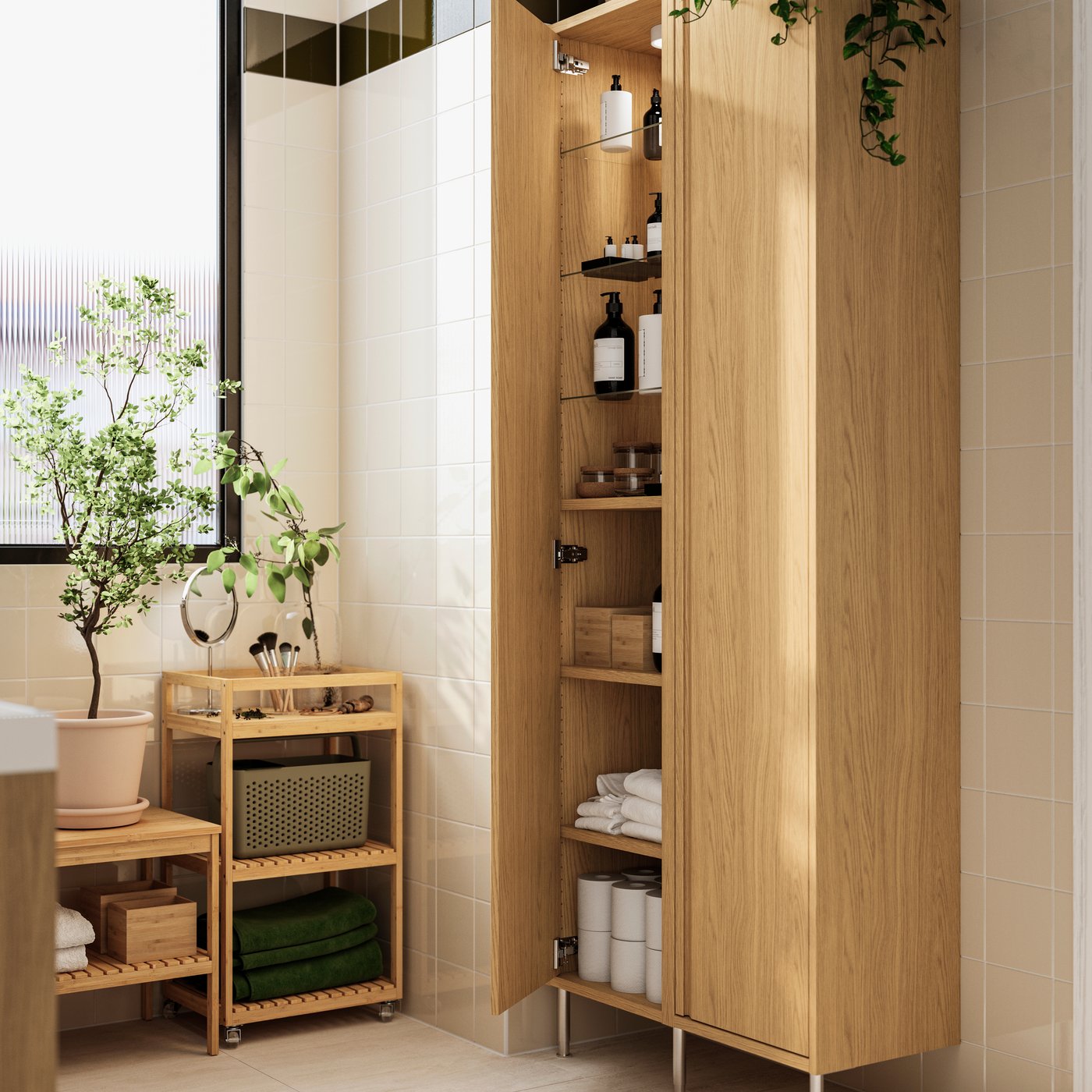 An oak effect ÄNGSJÖN high cabinet with legs has a door open, showing its shelves holding toilet paper rolls and toiletries.