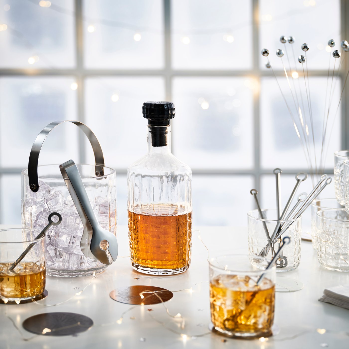 FRÖJDA whiskeyglas, karaffel og isspand på et nytårspyntet bord.