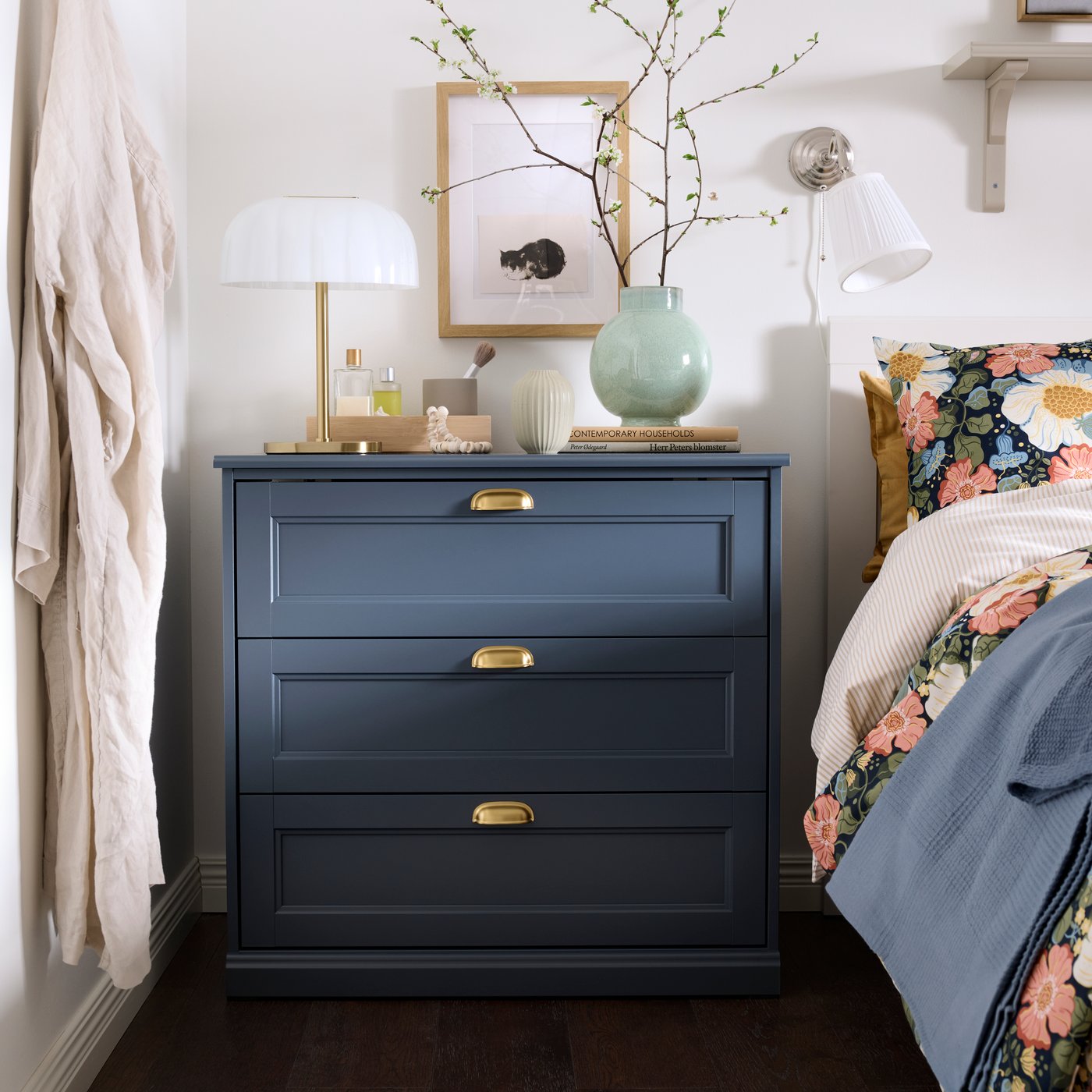 Eine blaue FÅGELFJÄLLET Kommode ist in einem hellen Schlafzimmer zu sehen.