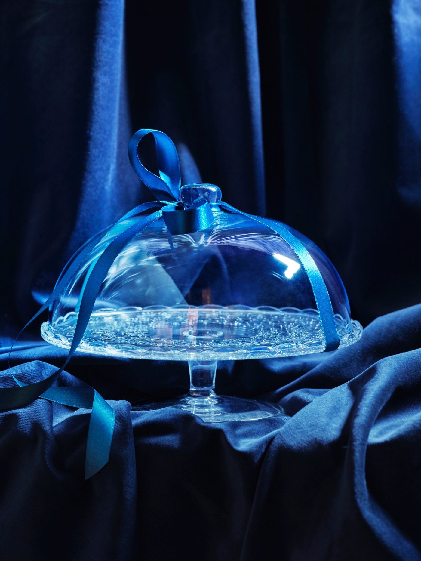 A clear glass ARV BRÖLLOP serving stand with lid in the dining room