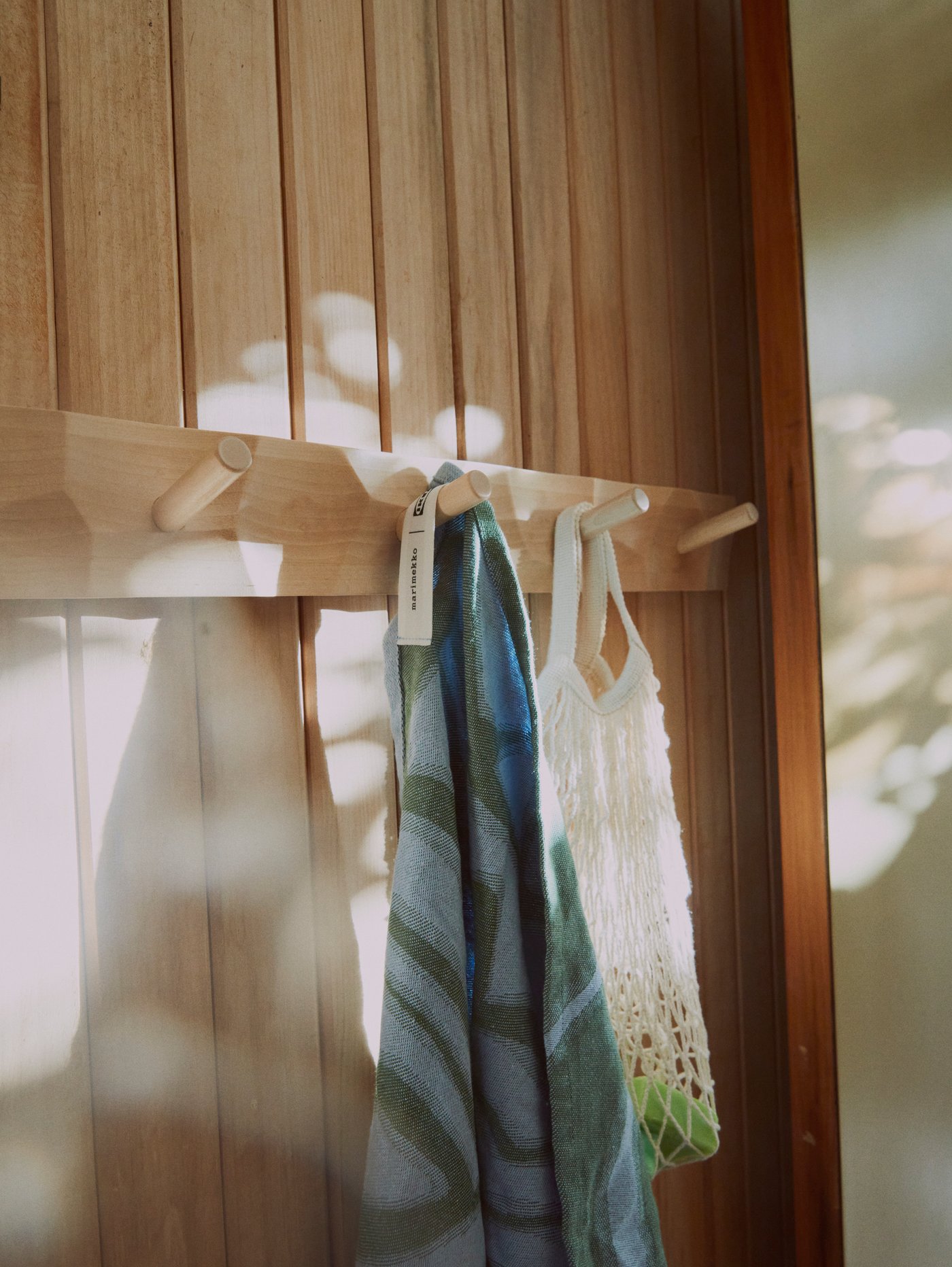 Zelený ručník visí na věšáku BASTUA s 5 knoflíky z masivní břízy.
