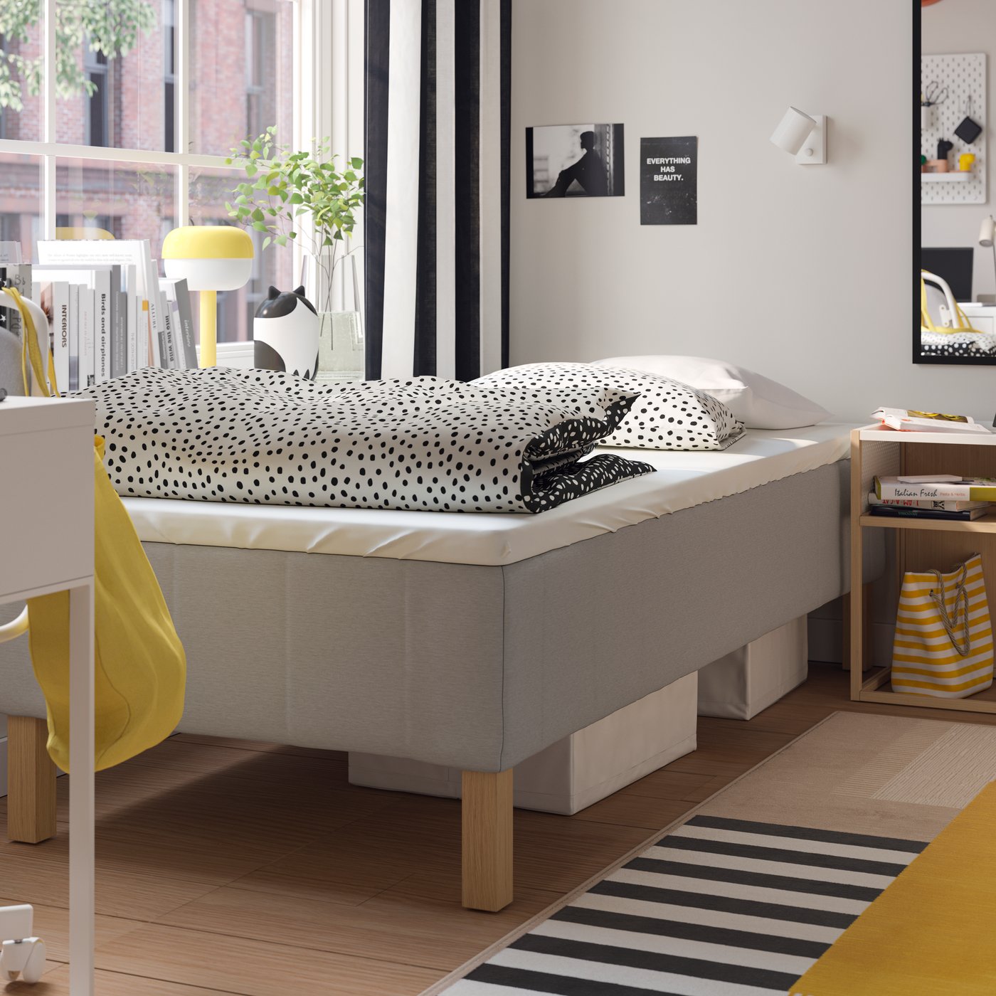 Two SKUBB storage cases lie under a RENFJÄLLET pocket spring mattress base with BJÖRKGRÅMAL bed linen in a bedroom.