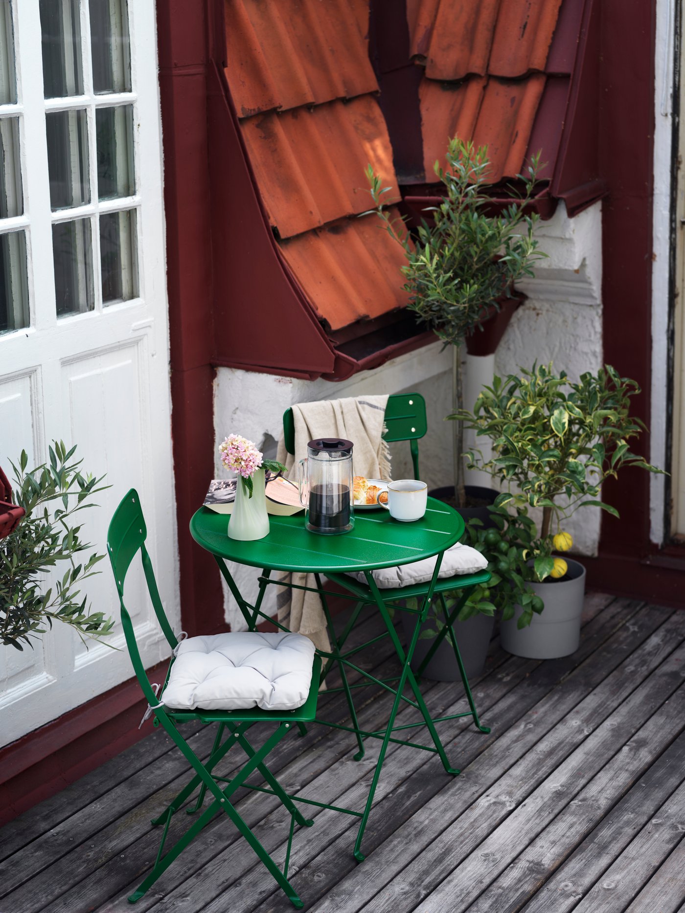 Et grønt SUNDSÖ bord og to SUNDSÖ stole står på en træterrasse.