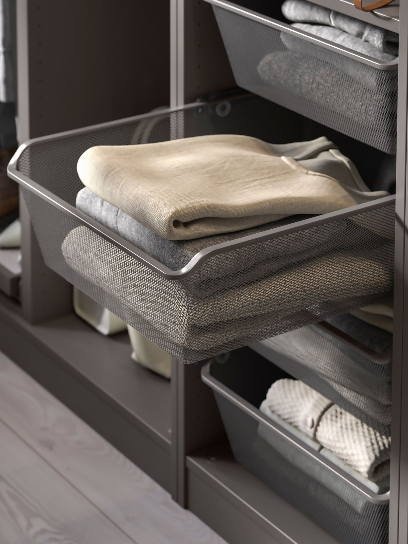 KOMPLEMENT wire-mesh baskets in a PAX wardrobe with clothes, one is pulled out.