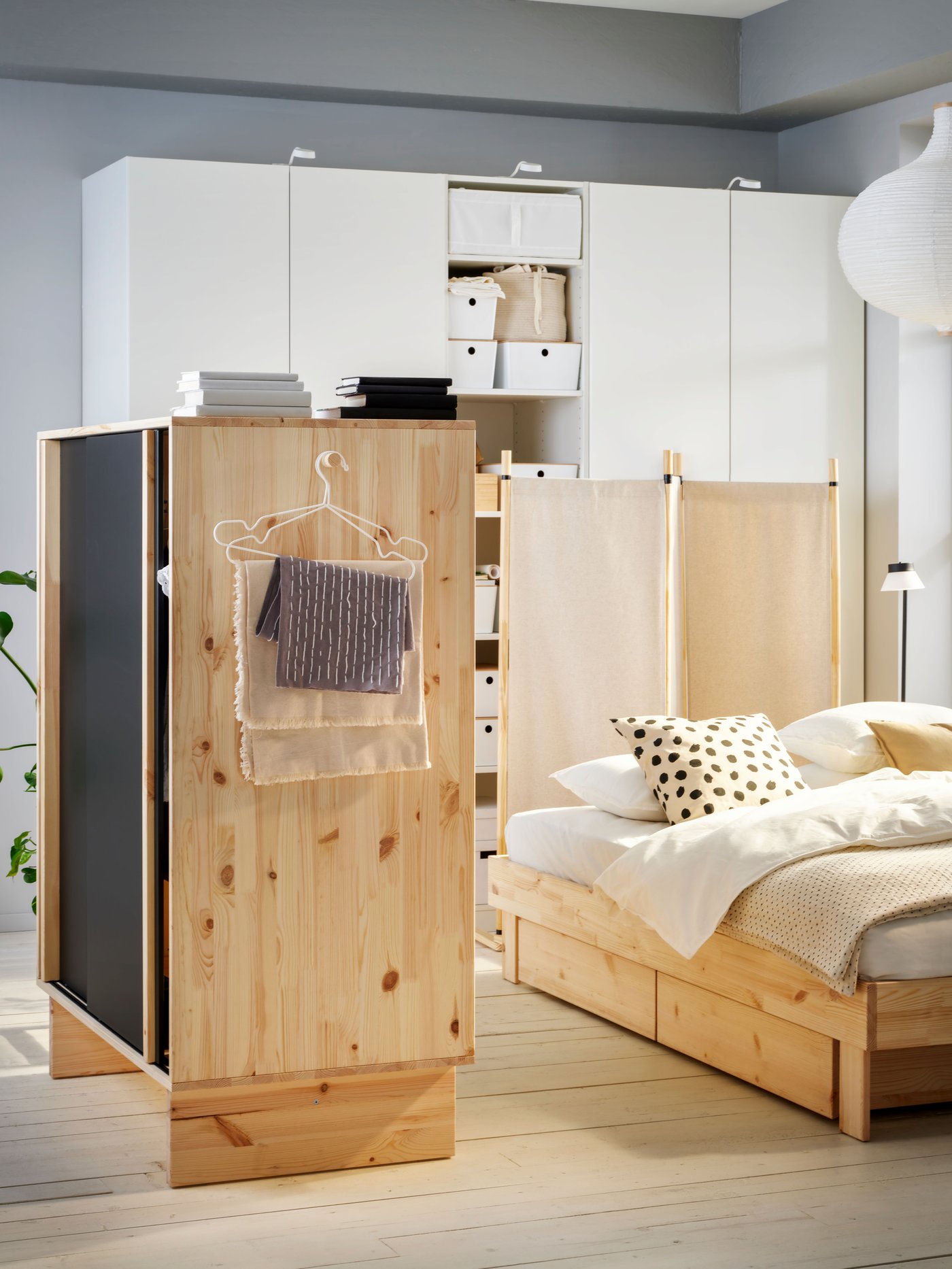A room featuring three GLAMBERGET pieces: a wardrobe with 3 sliding doors, an extendable bed with storage and a room divider.