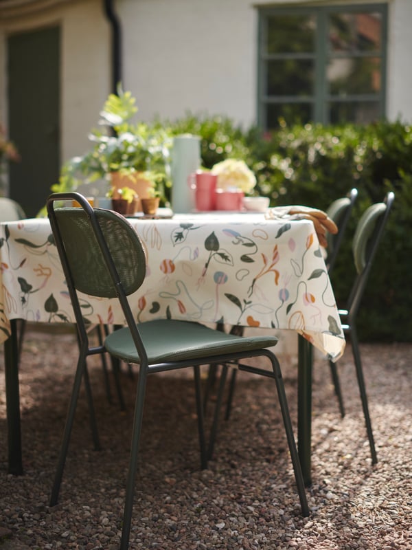 Una mesa de terraza con una silla ENSHOLM verde en la cabecera.