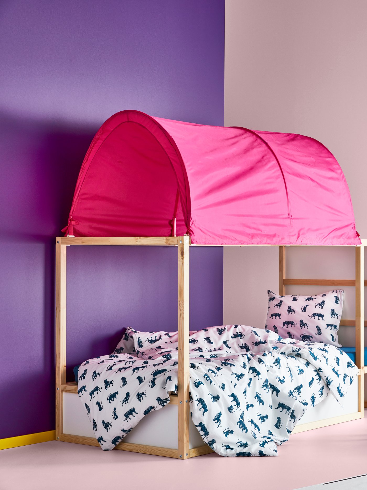 Dormitorio infantil con pared violeta, cama reversible, funda nórdica y funda de almohada con estampado azul y blanco, y tienda de campaña rosa.