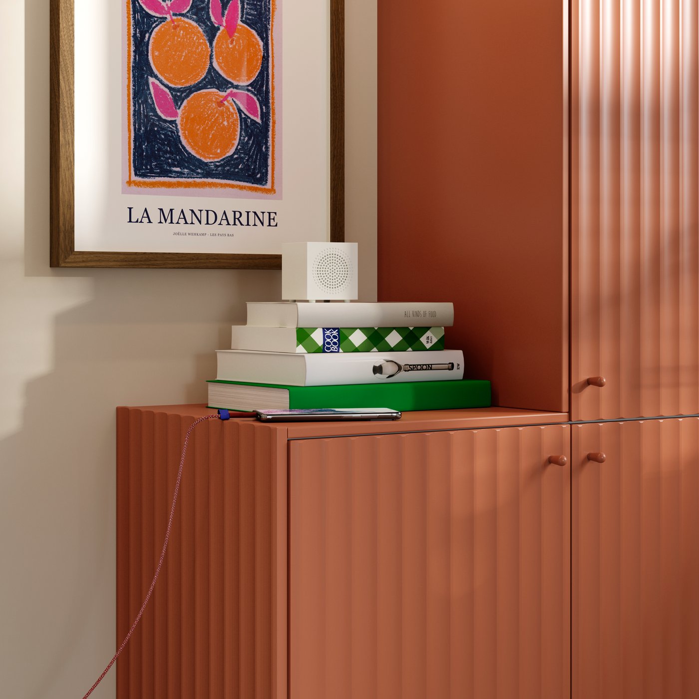 Some books and a Bluetooth speaker are placed on a kitchen cabinet with a TERRSJÖ accent door with a red-brown pattern.
