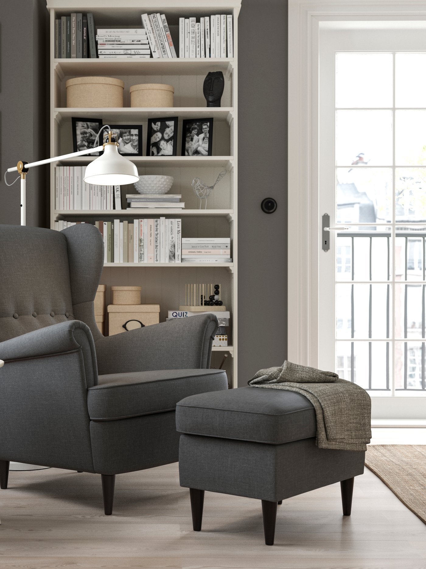A Nordvalla dark grey STRANDMON wing chair with a grey footstool in the living room.