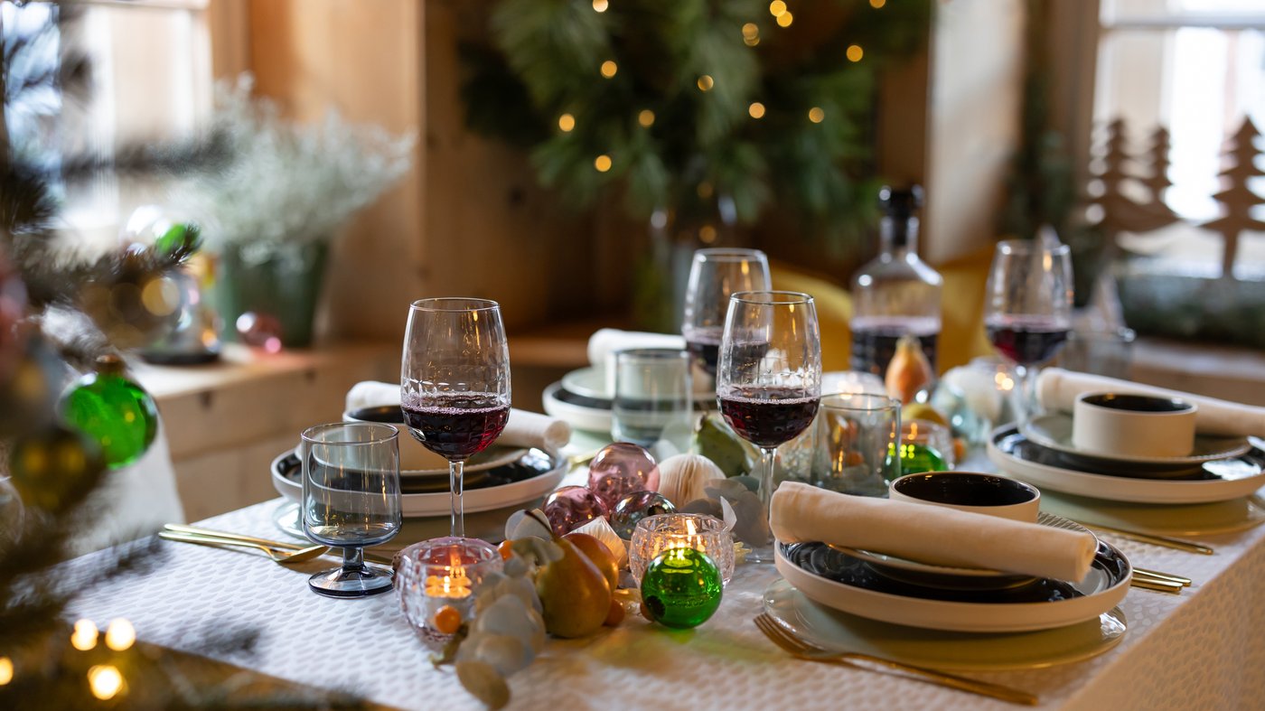 Auf einem festlichgedeckten Tisch befindet sich STRIMMIG und OMBONAD Essgeschirr und im Hintergrund sieht man verschwommen einen Christbaum