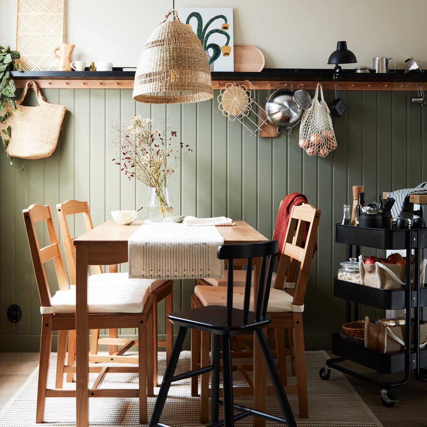 An antique stain pine HÄGERNÄS table and four chairs, and a black AGAM junior chair in a small rustic-style dining room.