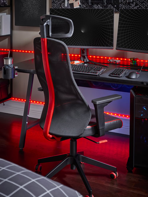 Workspace with a black gaming chair with adjustable height placed next to a rectangular desk supporting a gamin mouse pad.