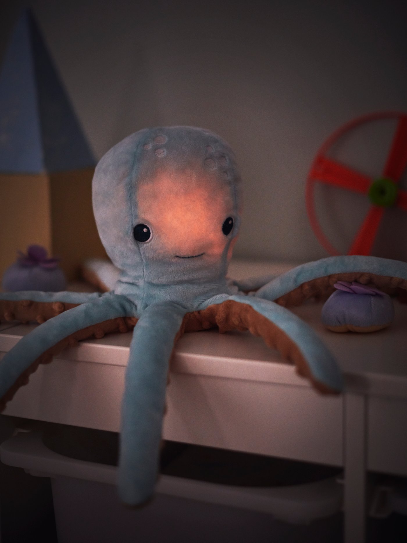 A turquoise BLÅVINGAD soft toy with LED night light, shaped like an octopus, sits on a TROFAST storage combination.