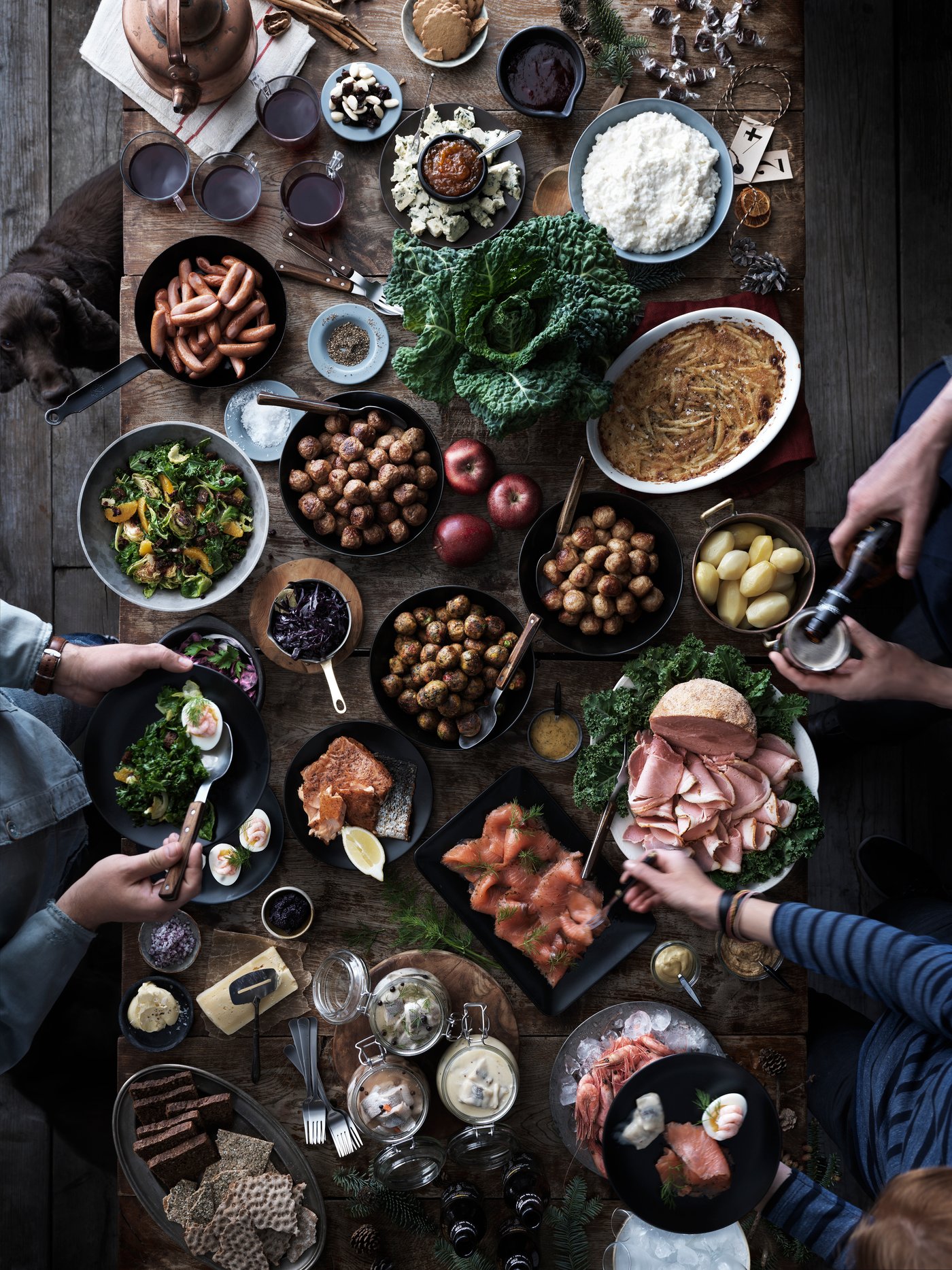 Groupe de personnes autour d’une table chargée des plats traditionnels du Noël suédois.