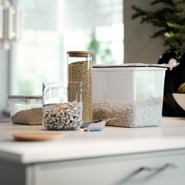 EKLATANT jar with lid filled with beans on a kitchen worktop, placed next to other clear food storage containers.