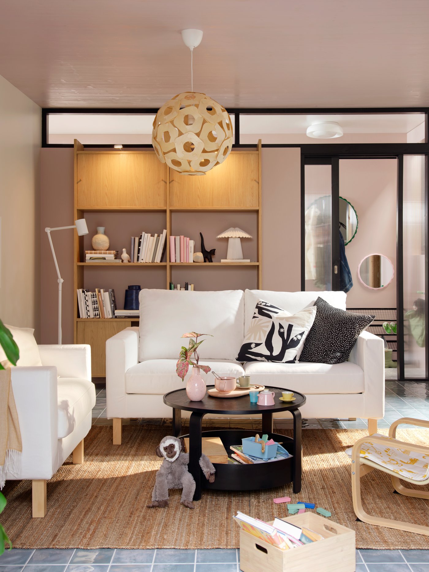 A light living room with a white SALTSJÖBADEN sofa-and armchair combination flanked by a BORGEBY coffee table and toys.