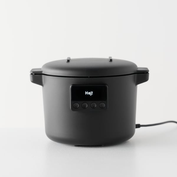 A white background features a black TILLREDA multicooker sitting on a counter with a simple design, cord and control panel.