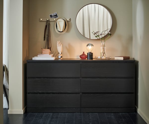 Un miroir suspendu au-dessus d’une commode.