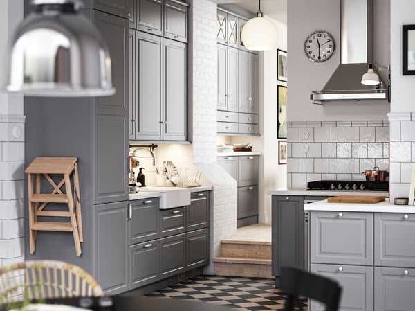 A traditional kitchen with a checkered floor, gray BODBYN kitchen fronts and white/light gray stone effect/laminate worktops.
