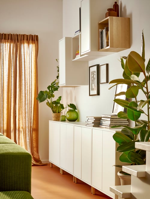 Living room with multiple cabinets with legs, multiple, wall-mounted cabinets, a potted plant, and a vase.