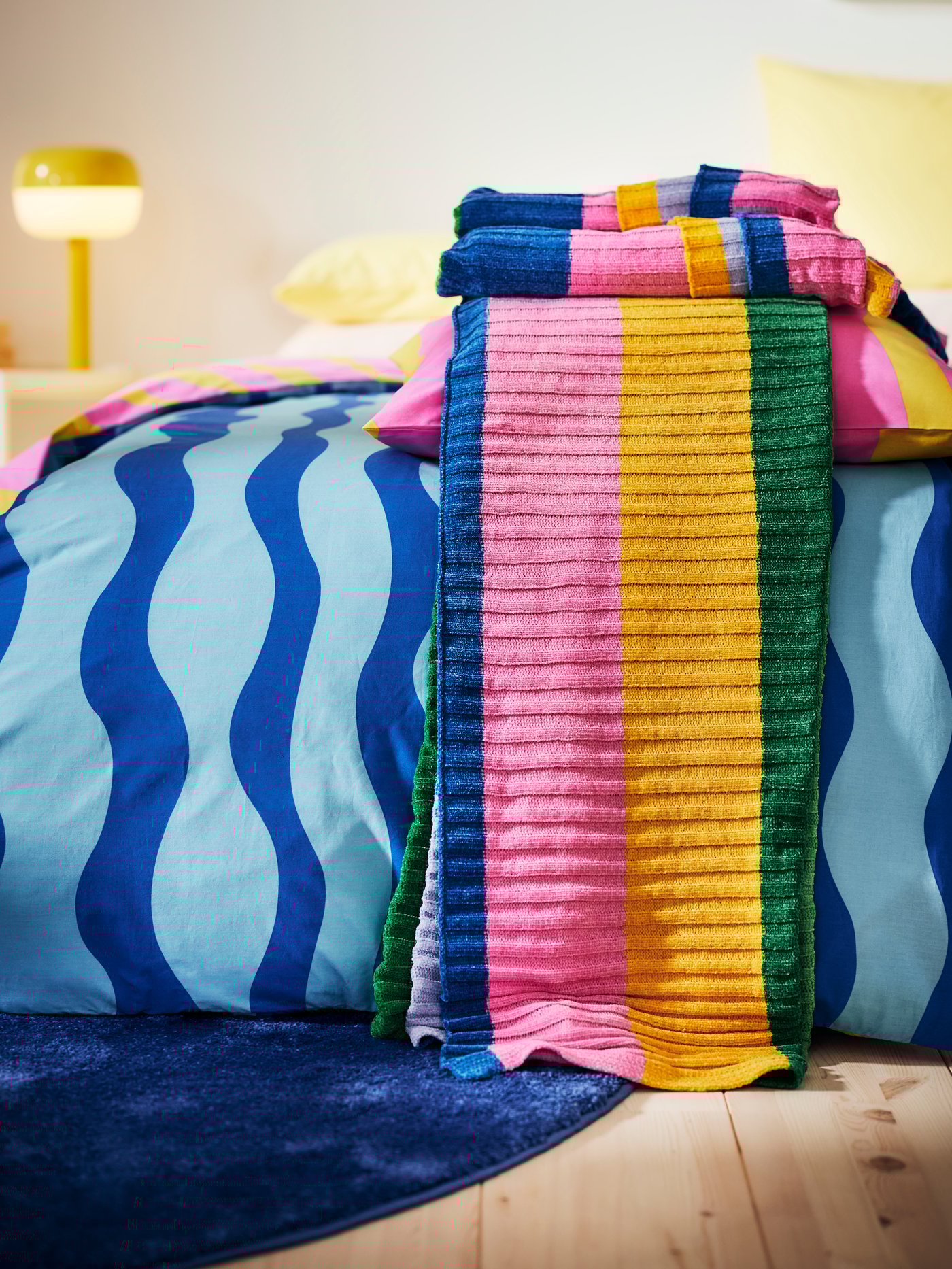 In the foreground is the FJÄLLTRIFT cuddly blanket and lies matching the SOMMARVICKER bedding set on the bed.