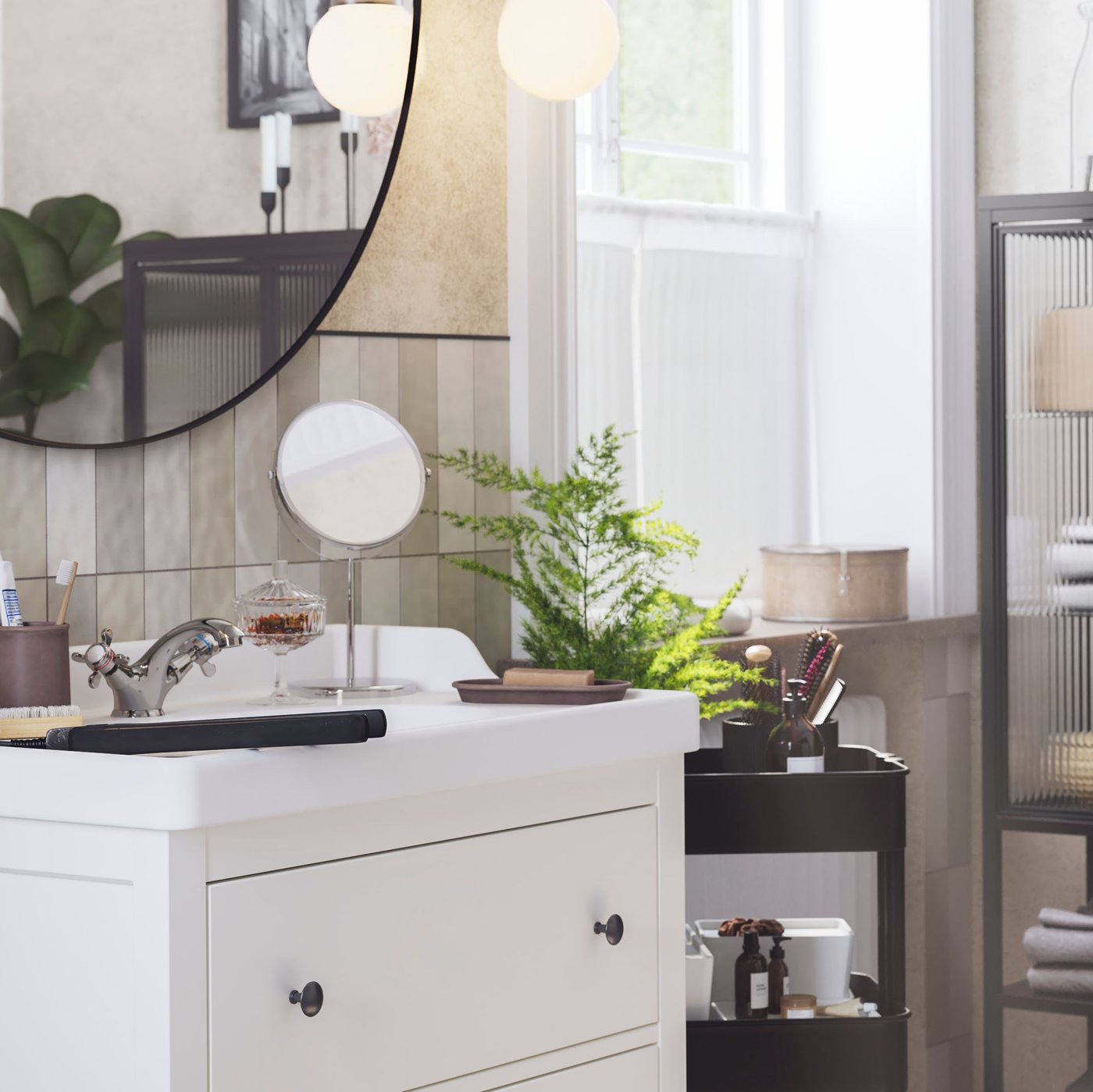 Un mirall LINDBYN penjat sobre un armari de lavabo HEMNES/RÄTTVIKEN amb dos calaixos de color blanc, al costat d'un llum de paret FRIHULT.