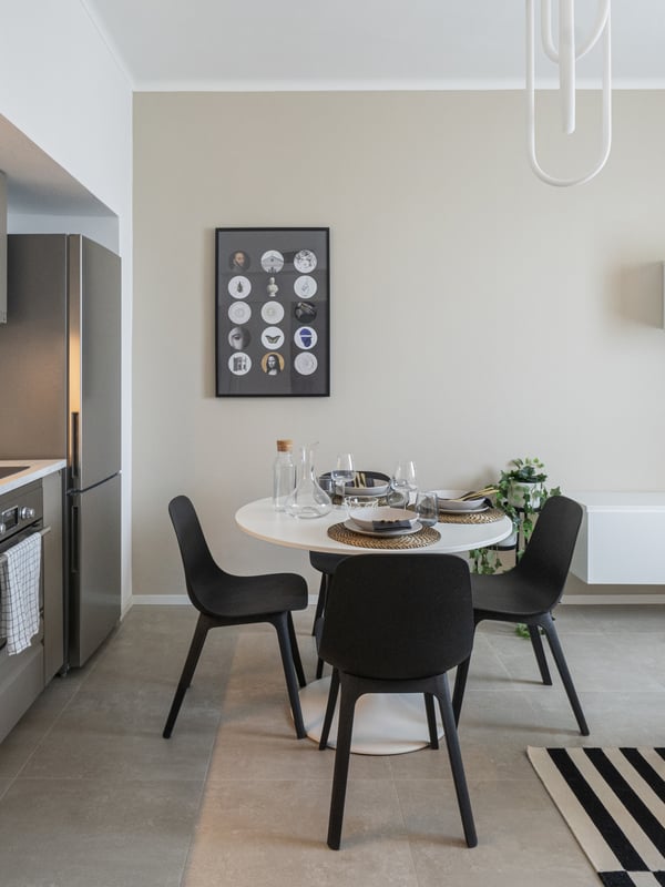 Un appartamento dall'aspetto moderno con una cucina IKEA grigia, tavolo da pranzo e sedie e un piccolo mobile TV a parete.