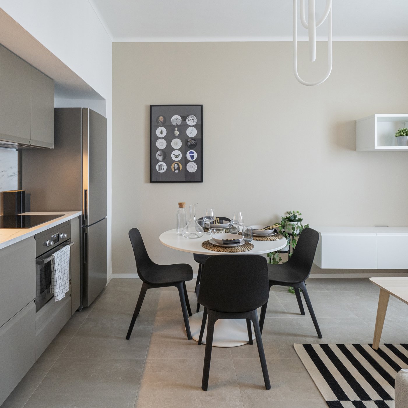 Piccolo monolocale con cucina grigia e pareti beige con mobili BESTA bianchi