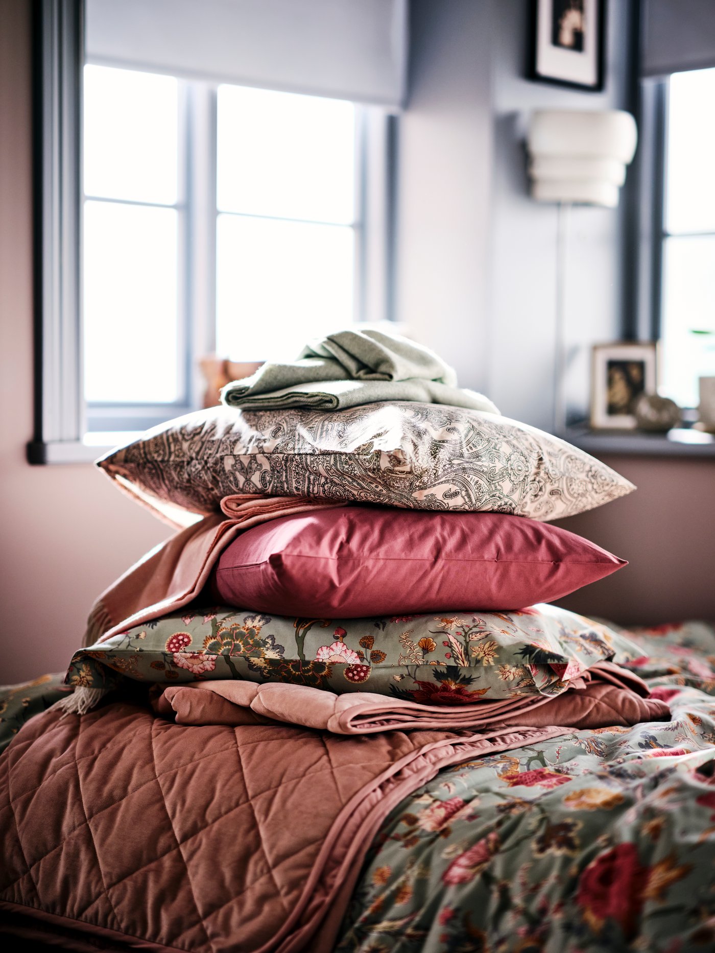 Stos poduszek leżących jedna na drugiej na łóżku.